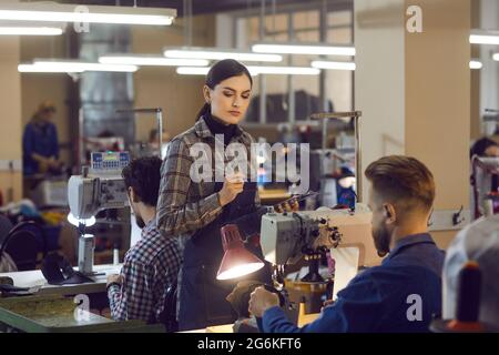 Weibliche Managerin, die die Qualität der Mitarbeiterarbeit in der Lederschuhfabrik überprüft Stockfoto