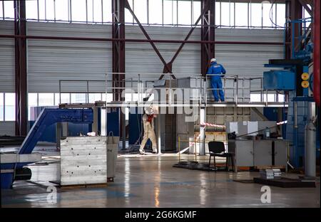 Atyrau, Kasachstan: Schweißer und weißer Anzug arbeitet in der Werkshalle Kazturboremont (KTR).Bau eines Stahlpodests. Arbeiter in Blau Arbeitskleidung. Stockfoto