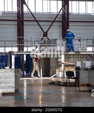 Atyrau, Kasachstan-Mai 21,2012: Schweißer un weißen Anzug Herstellung Stahl poduim. Werkstätte Kazturboremont (KTR). Arbeiter in blauer Arbeitskleidung und weißer helme Stockfoto