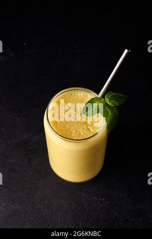 Lassi in Glas mit Rohr auf dunklem Hintergrund vertikale Ausrichtung. Traditionelles indisches und pakistanisches kaltes Erfrischungsgetränk Stockfoto