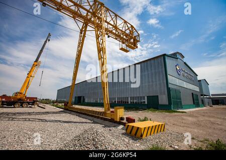 Region Almaty, Kasachstan-Juni 06,2012: INDUSTRIEGEBIET DAMU. Neues Sonik-Fabrikgebäude. Grüne Tore, Eisenbahn, gelbe Gantry und LKW-Krane links. S Stockfoto