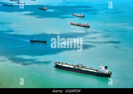 Luftaufnahme von Containerschiffen in der Straße von Singapur. Flugzeugshot. Frachtschiffe ankerten auf der Straße und warteten darauf, den verkehrsreichsten Hafen der Region zu erreichen. Stockfoto