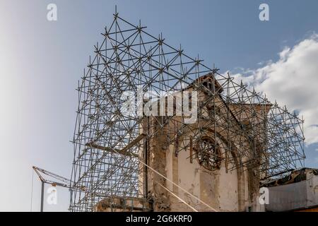 Die Basilika San Benedetto, die vom Erdbeben schwer getroffen wurde, ist in der untergehenden Sonne, Norcia, Italien, mit Gerüsten bedeckt Stockfoto