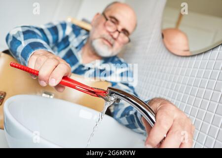 Klempner Handwerker montiert neuen Wasserhahn auf Waschbecken Stockfoto