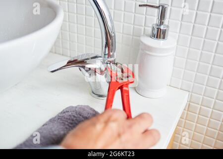 Klempner Hand mit Rohrschlüssel, während die Installation eines Waschbecken Wasserhahn im Badezimmer Stockfoto