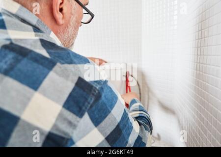 Handwerker Klempner montiert oder repariert defekte Toilettenzisterne in der Toilette Stockfoto