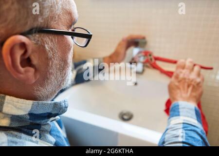 Handwerker Klempner oder Handwerker repariert gebrochenen Wasserhahn im Badezimmer Stockfoto