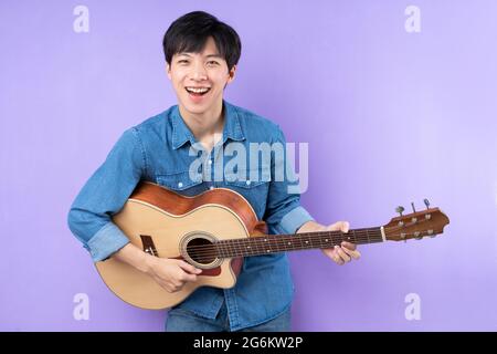 Porträt eines asiatischen Mannes in blauem Hemd, der auf purpurem Hintergrund posiert Stockfoto