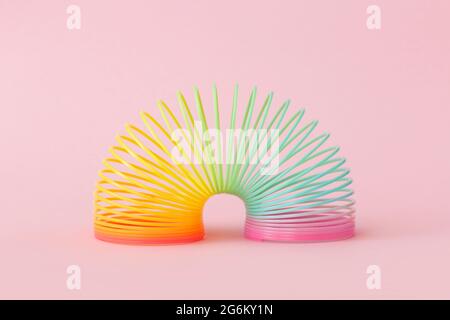 Regenbogen Plastikfederspielzeug auf rosa Hintergrund Stockfoto