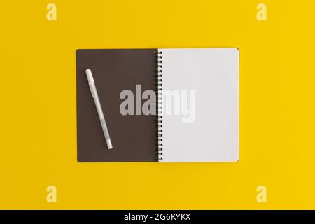 Notizbuch und Stift auf gelbem Hintergrund. Draufsicht. Flach liegend. Zurück zum Schulkonzept.Notizbuch und Stift auf gelbem Hintergrund. Draufsicht. Flach liegend. Zurück zu s Stockfoto