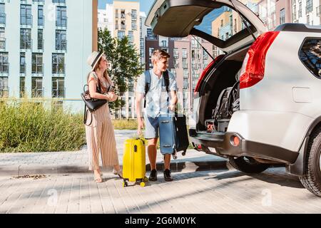 Paar sammeln für Road Trip. Putting Taschen auf Auto-Kofferraum. Sommerferien Stockfoto