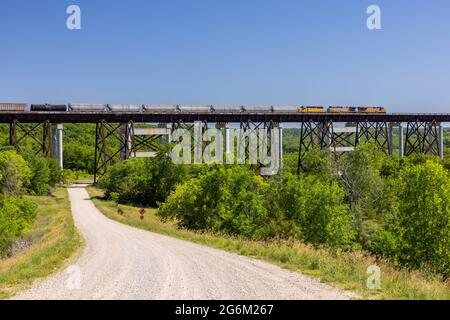 Ein Güterzug, der eine hohe Böstelbrücke überquert. Stockfoto