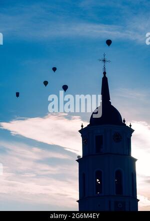 Silhouette von Glockenturm und Luftballons am Himmel am Abend in Vilnius, Litauen, vertikal Stockfoto