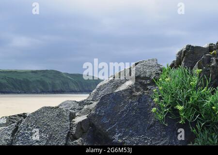 Eine wunderschöne Aussicht auf eine Küstenwanderung in North Devon, mit detailliertem Fokus von einer Felsformation auf dem Putsborough Sands an einem klassischen britischen Sommertag. Stockfoto