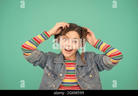 Ich liebe es, Haare zu machen. Glückliches Mädchen tun Haare blauen Hintergrund. Beauty-Look des kleinen Kindes. Friseursalon. Haarpflegekosmetik. Shampoo-Produkte. Stolz zu sein Stockfoto