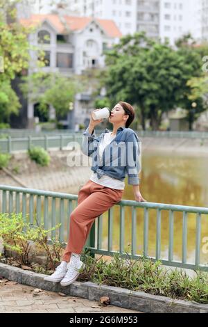 Glückliche junge Frau genießt Kaffee trinken vor städtischem Hintergrund. Stockfoto