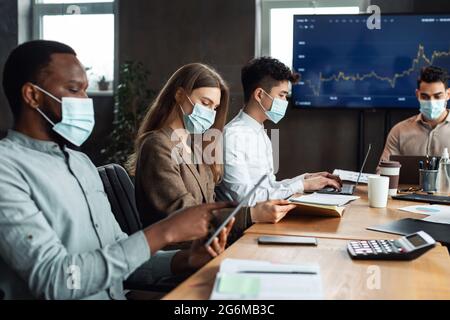 Kollegen, die an einem Projekt mit Gesichtsmasken arbeiten Stockfoto