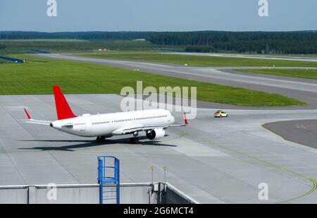 Das Auto begleitet ein Passagierflugzeug zur Start- und Landebahn. Stockfoto