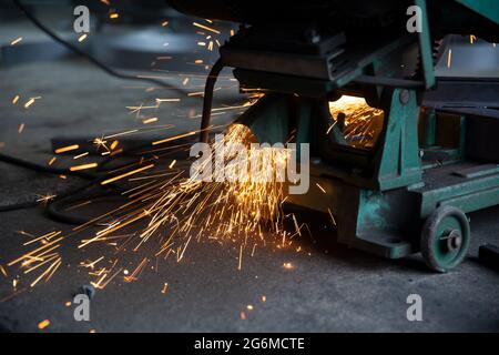 Schweißer verwendete Schleifstein auf Stahl in der Fabrik mit Funken, Schweißprozess in der Industriewerkstatt, Hände mit Instrument im Rahmen. Stockfoto