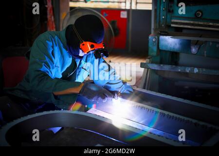 Schweißer verwendete Schleifstein auf Stahl in der Fabrik mit Funken, Schweißprozess in der Industriewerkstatt, Hände mit Instrument im Rahmen. Stockfoto