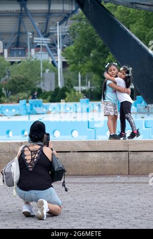 Eine Mutter, die Fotos von 2 entzückenden Töchtern auf dem Handy gemacht hat. Im Flushing Meadows Corona Park in der Nähe des Unispahere in Queens, New York City. Stockfoto