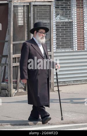 Ein älterer orthodoxer jüdischer Mann mit einem Stock geht auf der Lee Avenue. In Williamsburg, Brooklyn, New York City. Stockfoto