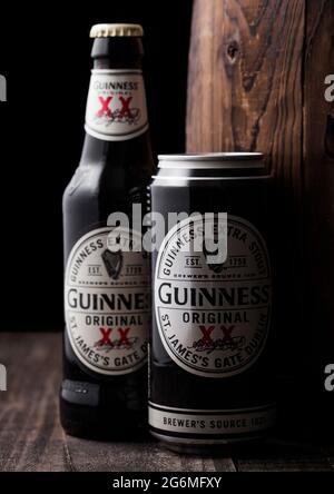 LONDON, Großbritannien - 27. APRIL 2018: Aluminiumdose und eine Flasche Guinness extra stout Bier neben altem Holzfass. Guinness Bier wird seit 1 hergestellt Stockfoto