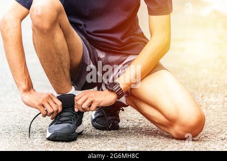 Läufer binden ihre Schnürsenkel, Er läuft im Park. Nahaufnahme Mann bindet Joggingschuhe. Stockfoto
