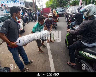 Jakarta, Indonesien. Juli 2021. Verwandte von Covid-19-Patienten sahen, wie sie eine Sauerstoffflasche außerhalb des Sauerstofffüllzentrums hoben, da die Nachfrage nach dem Gas aufgrund des Anstiegs bei Coronavirus-Fällen steigt. Der Anstieg der schrecklichen Coronavirus-Fälle hat in Indonesien zu Sauerstoffmangel geführt, wie der Sauerstofflieferant am Dienstag mitteilte. (Foto von Agung Fatma Putra/SOPA Images/Sipa USA) Quelle: SIPA USA/Alamy Live News Stockfoto