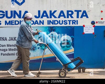 Jakarta, Indonesien. Juli 2021. Ein Mann, der einen Wagen mit einer Sauerstoffflasche vor dem Sauerstofffüllzentrum schiebt, da die Nachfrage nach dem Gas aufgrund des Anstiegs bei Coronavirus-Fällen steigt. Der Anstieg der schrecklichen Coronavirus-Fälle hat in Indonesien zu Sauerstoffmangel geführt, wie der Sauerstofflieferant am Dienstag mitteilte. Kredit: SOPA Images Limited/Alamy Live Nachrichten Stockfoto