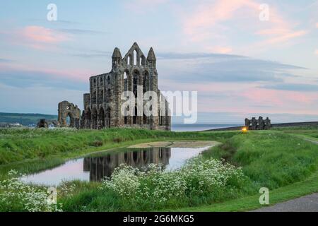 Whitby Abbey bei Sonnenaufgang spiegelte sich im Teich wider Stockfoto