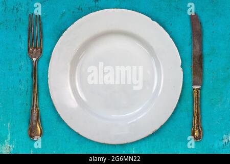 Retro-Stil Bild eines leeren Essteller mit Gabel und Messer auf blauem Hintergrund Stockfoto