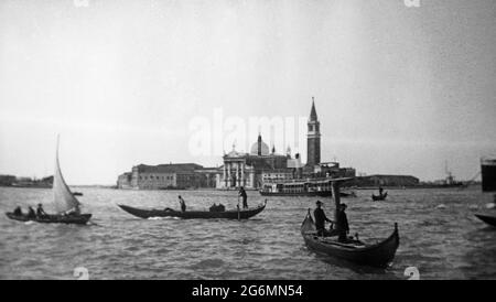 Ein altes Schwarz-Weiß-Foto aus dem frühen 20. Jahrhundert, das einen Kanal in Venedig, Italien, mit Gondoliern in ihren Gondeln zeigt. Stockfoto