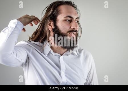 Porträt eines jungen Geschäftsmannes aus dem Nahen Osten mit Bart und langen Haaren, die seine Haare justieren Stockfoto