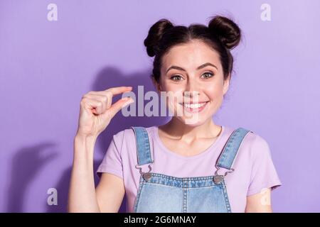 Foto von süß glänzend junge Dame tragen Jeans insgesamt Messung Finger kleinen leeren Raum isoliert violette Farbe Hintergrund Stockfoto