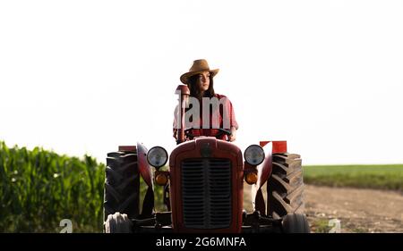 Bäuerin, die einen Traktor auf dem Feld fährt Stockfoto