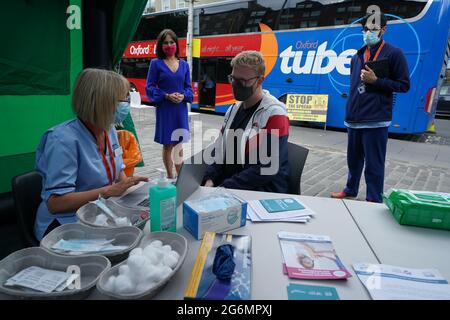 Schottlands stellvertretende Chief Medical Officer Dr. Nicola Steedman beobachtet, wie sich Krankenschwester Susan Pate während eines Besuchs in einem Impfbus des Scottish Ambulance Service und des NHS Lothian auf dem Grassmarket in Edinburgh auf die Verwaltung eines Impfjabs für Maurice Hickman vorbereitet. Bilddatum: Mittwoch, 7. Juli 2021. Stockfoto