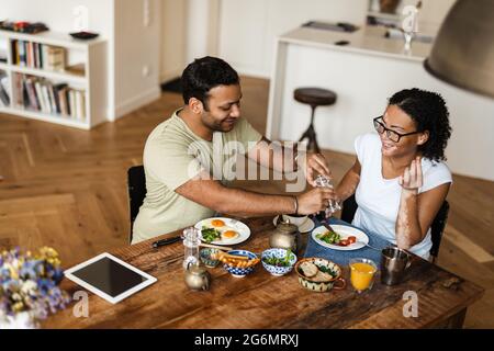 Mann und Frau aus dem Nahen Osten lächeln beim Frühstück in der Küche zu Hause Stockfoto