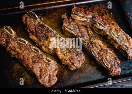 Gegrilltes Rindfleisch kurze Rippen auf einer Pfanne: Grill flankiert Rindfleisch Rippen mit einem rustikalen Hintergrund Stockfoto