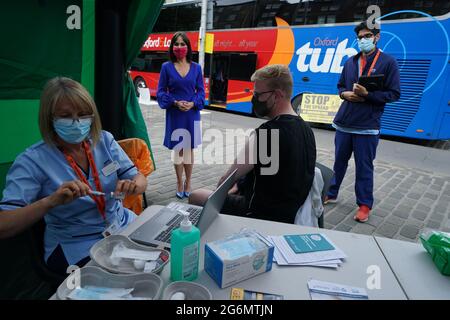 Schottlands stellvertretende Chief Medical Officer Dr. Nicola Steedman beobachtet, wie sich Krankenschwester Susan Pate während eines Besuchs in einem Impfbus des Scottish Ambulance Service und des NHS Lothian auf dem Grassmarket in Edinburgh auf die Verwaltung eines Impfjabs für Maurice Hickman vorbereitet. Bilddatum: Mittwoch, 7. Juli 2021. Stockfoto