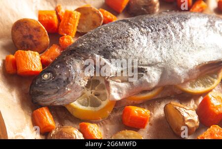 Eine ganze gebackene Regenbogenforelle mit geröstetem Wurzelgemüse Stockfoto