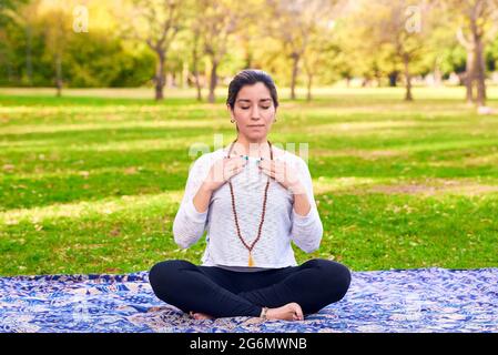 Lateinische Frau, die Reiki posiert, in einem Park. Yoga-Meditation. Stockfoto