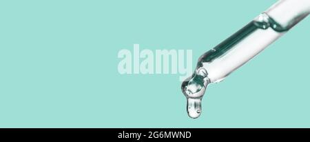 Nahaufnahme der kosmetischen Pipette mit ätherischem Öltropfen, Serum mit Peptiden, Hyaluronsäure auf blauem Hintergrund. Tropf, fallender Tropfen aus nächster Nähe. Selbst Stockfoto