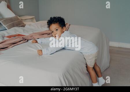 Süßer kleiner afroamerikanischer Junge, der zu Hause im gemütlichen Schlafzimmer spielt Stockfoto