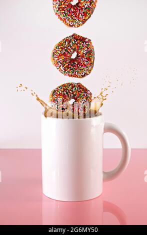 Donut spritzt in einer riesigen Tasse schwarzen Kaffee Stockfoto