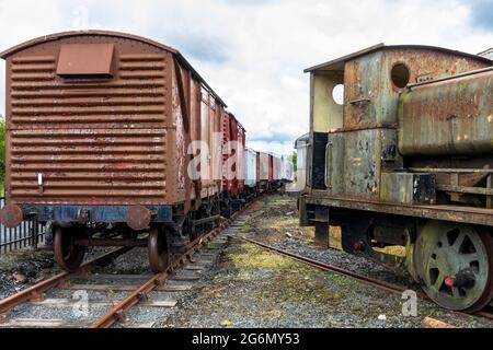 Alte Güterwagen und Teil einer Barclay 0-4-0 Satteltanklokomotive in einem Nebengleis in Dunaskin, Ayrshire, Schottland, Großbritannien Stockfoto