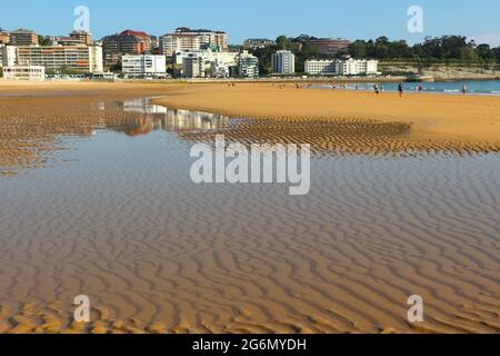 Blick auf den Strand mit reflektierten Gebäuden in einem Pool mit Meerwasser an einem sonnigen Frühlingsmorgen Sardinero Santander Cantabria Spanien Stockfoto