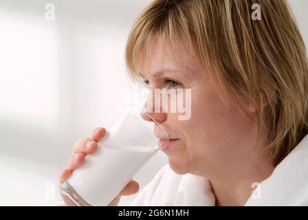 Weibliche Patientin, die Bariumsulfat-Suspension aus einem Glas trinkt Stockfoto