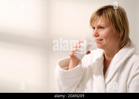 Weibliche Patientin, die Bariumsulfat-Suspension aus einem Glas trinkt Stockfoto