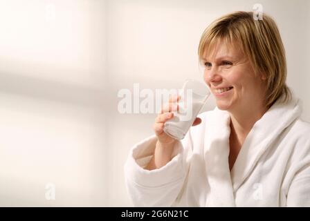 Weibliche Patientin, die Bariumsulfat-Suspension aus einem Glas trinkt Stockfoto